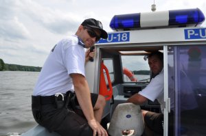 Zdjęcie kolorowe. Policjanci z posterunku wodnego na łodzi służbowej.
