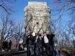 Zdjęcie kolorowe. Pięciu mężczyzn pozujących do zdjęcia na tle historycznej wieży.