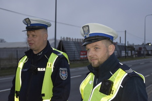 Zdjęcie kolorowe. Policjanci z ruchu drogowego w umundurowaniu służbowym i kamizelkach odblaskowych podczas akcji &quot;Prędkość&quot;.