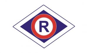 Grafika. Logo ruchu drogowego. Wielka litera R koloru niebieskiego na białym tle, w czerwonym okręgu na rombie koloru granatowego otoczonym białą obwódką