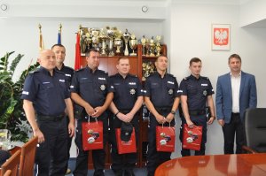 Zdjęcie kolorowe. Burmistrz Gminy Opatówek Sebastian Wardęcki, Zastępca Komendanta Miejskiego Policji w Kaliszu Witold Goździelewski oraz Komendant Komisariatu Policji w Opatówku asp. Tomasz Dyrdziak z czterema wyróżnionymi policjantami.