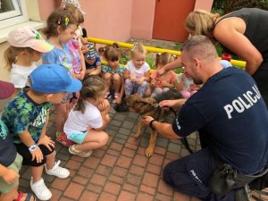 zdjęcie kolorowe, na fotografii przewodnik psa służbowego wraz z przedszkolakami podczas spotkania