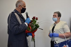 Zdjęcie kolorowe. Komendant Miejski Policji w Kaliszu insp. Dariusz Bieniek wręcza kwiaty Pani Marii Szcześniak, która dzień wcześniej przeszła na emeryturę.