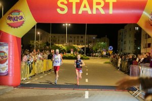 Zdjęcie kolorowe. Dwójka biegaczy wbiega na metę III Kaliskiego Nocnego Półmaratonu &quot;Bursztynowa Hellena&quot;.