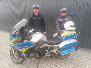 zdjęcie przedstawia dwóch umundurowanych funkcjonariuszy Wydziału Ruchu Drogowego przy policyjnym motocyklu