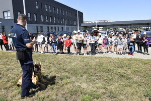 zdjęcie kolorowe, na nim policjant-przewodnik psa służbowego oraz dzieci