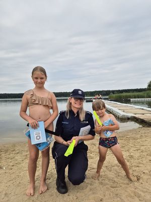 Pierwsze zdjęcie kolorowe , na nim osoby wypoczywające nad wodą oraz policjantka w tle rozmawiająca z dzieckiem.
Drugie zdjęcie kolorowe na nim policjantka rozmawiająca z osobami przebywającymi nad wodą.
Trzecie zdjęcie kolorowe, na nim policjantka z dziećmi na plaży.
Czwarte zdjęcie kolorowe, na nim policjantka z dziećmi na plaży udzielająca porad na temat bezpieczeństwa nad wodą.
Piąte zdjęcie kolorowe, przedstawia policjantkę wręczającą ulotkę ,,kręci mnie bezpieczeństwo nad wodą&#039;&#039; plażowiczom.
Szóste zdjęcie kolorowe na nim policjantka przekazuję ulotkę pani siedzącej na plaży przy zalewie Murowaniec.