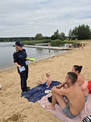 Pierwsze zdjęcie kolorowe , na nim osoby wypoczywające nad wodą oraz policjantka w tle rozmawiająca z dzieckiem.
Drugie zdjęcie kolorowe na nim policjantka rozmawiająca z osobami przebywającymi nad wodą.
Trzecie zdjęcie kolorowe, na nim policjantka z dziećmi na plaży.
Czwarte zdjęcie kolorowe, na nim policjantka z dziećmi na plaży udzielająca porad na temat bezpieczeństwa nad wodą.
Piąte zdjęcie kolorowe, przedstawia policjantkę wręczającą ulotkę ,,kręci mnie bezpieczeństwo nad wodą&#039;&#039; plażowiczom.
Szóste zdjęcie kolorowe na nim policjantka przekazuję ulotkę pani siedzącej na plaży przy zalewie Murowaniec.