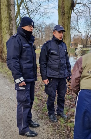 Zdjęcie kolorowe. Policjanci podczas rozmowy z mieszkańcem w Parku Miejskim