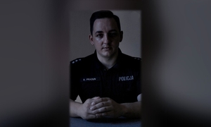 zdjęcie kolorowe, na zdjęciu policjant siedzący przy stole