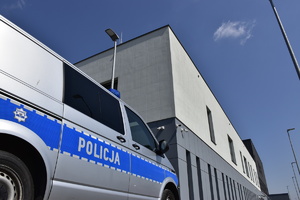 zdjęcie kolorowe, na zdjęciu radiowóz policyjny na tle budynku komendy miejskiej policji w kaliszu