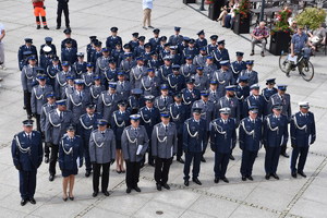 Zdjęcie kolorowe z góry. Pododdział policjantów ustawiony w formie kwadratu na Głównym Rynku w Kaliszu podczas uroczystości obchodów Święta Policji . Po lewej stronie stoi dowódca pododdziału.