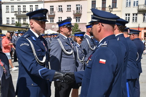 Zdjęcie kolorowe. Rząd Policjantów odbierający gratulacje od przedstawicieli Związków Zawodowych i przełożonych za odznaczenia które otrzymali.