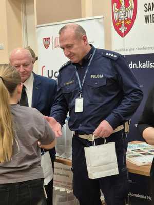 Zdjęcie kolorowe. Dwóch organizatorów konkursu - Moja bezpieczna droga do szkoły - w kasku zawsze bezpieczniej, wręcza nagrody uczestniczce konkursu.