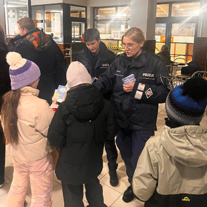 Zdjęcie kolorowe. Policjantki rozdają dzieciom ulotki dotyczące akcji "Kręci mnie bezpieczeństwo w zimie".