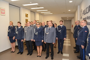Zdjęcie kolorowe. Policjanci w umundurowaniu wyjściowym stoją w rzędach czekając na wręczenie aktów mianowania.