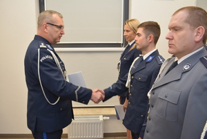 Zdjęcie kolorowe. Komendant Miejski Policji w Kaliszu wręcza akt minowania i gratuluje uściskiem dłoni awansowanemu funkcjonariuszowi.