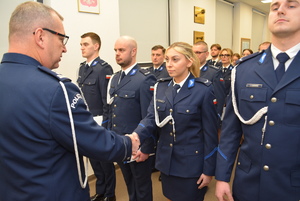 Zdjęcie kolorowe. Komendant Miejski Policji w Kaliszu wręcza akt minowania i gratuluje uściskiem dłoni awansowanej policjantce.