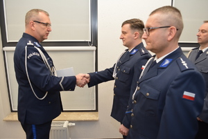 Zdjęcie kolorowe. Komendant Miejski Policji w Kaliszu wręcza pochwałę i gratuluje uściskiem dłoni wyróżnionemu funkcjonariuszowi.
