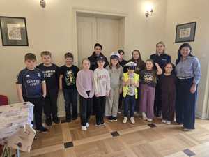 zdjęcie kolorowe zdjęcie grupowe na zdjęciu policjantka i przedstawiciel sanepidu i dzieci biorące udział w półkoloniach