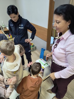 zdjęcie kolorowe na zdjęciu policjantka i przedstawiciel sanepidu podczas spotkania z dziećmi na półkoloniach
