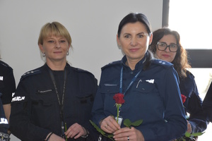 Zdjęcie kolorowe. Dwie policjantki z trzymające czerwone róże w dłoniach.
