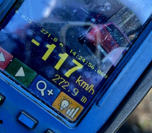 Zdjęcie kolorowe. Fragment wyświetlacza ręcznego miernika prędkości, na którym widnieje zdjęcie motocyklisty i jadących za nim dwóch pojazdów. W dolnej części pomiar prędkości - 117 km/h. Nad nim godzina pomiaru 14:24:56,869, pod nim odległość z której mierzono pojazd 272.9 m