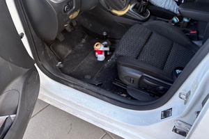 Zdjęcie kolorowe. Wnętrze pojazdu. Na podłodze stoi puszka i butelka po alkoholu.