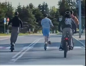 zdjęcie kolorowe, na zdjęciu cztery osoby, które jadą hulajnogami po jezdni