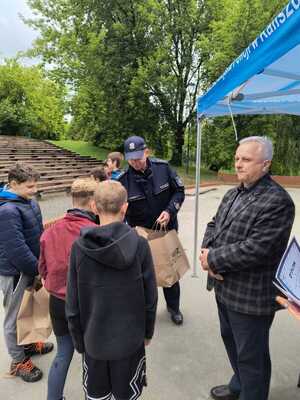 Zdjecie kolorowe. dzieci uczestniczące w "Biegu Urwisa" odbierają nagrody z rąk policjanta. Obok, pod namiotem stoi mężczyzna.