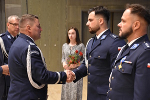 Komendant Wojewódzki gratuluje policjantowi awansu na wyższy stopień oficerki. Obok stoi kolejny awansowany policjant.