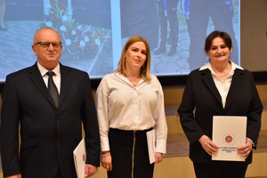 Troje pracowników Komendy Miejskiej Policji w Kaliszu (dwie kobiety i mężczyzna) stoją na scenie z odebranymi chwilę wcześniej listami gratulacyjnymi Związków Zawodowych Pracowników Cywilnych Policji.
