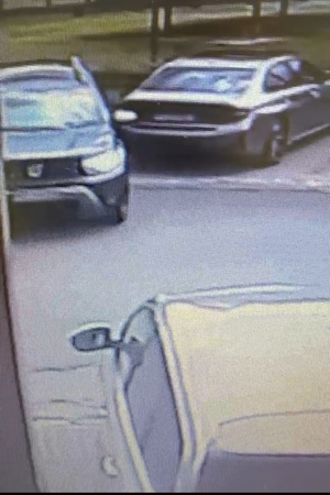 Zrzut z ekranu na którym widać pojazd marki Dacia, który wyjeżdża z miejsca parkingowego. Obok stoi zaparkowane BMW. Po przeciwnej stronie drogi widać fragment zaparkowanego auta.