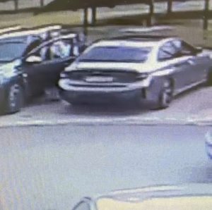 Zrzut z ekranu na którym widać pojazd marki Dacia, który wyjeżdża z miejsca parkingowego. Obok stoi zaparkowane BMW. Po przeciwnej stronie drogi widać fragment zaparkowanego auta.